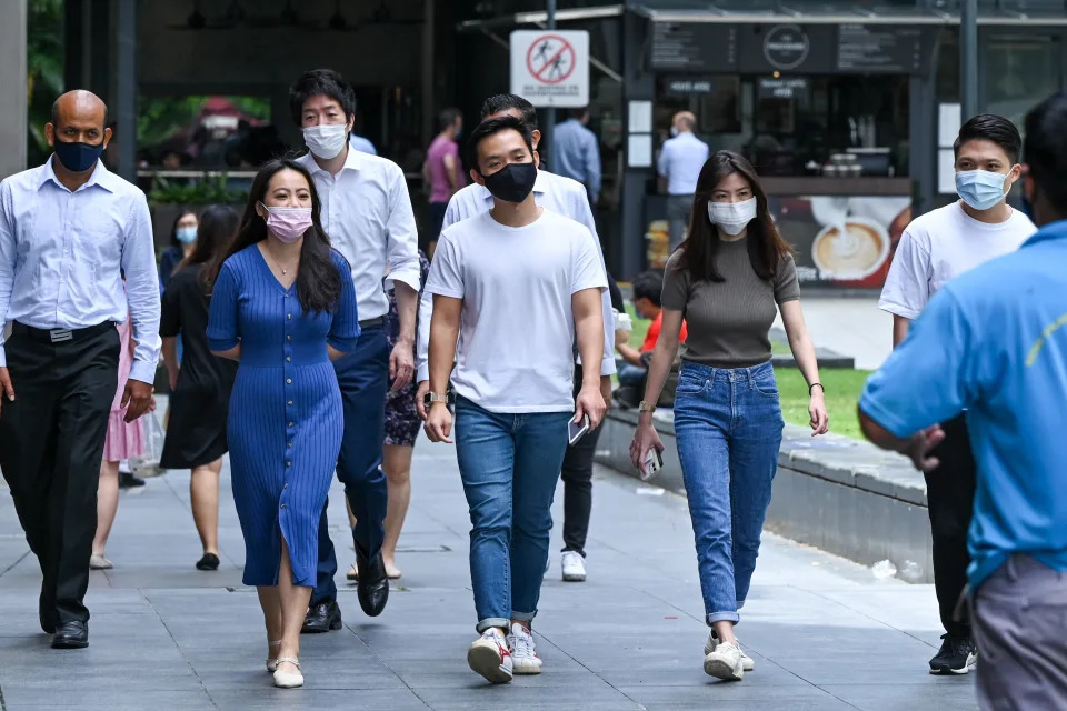 In this photograph taken on February 18, 2022, office workers go out for their lunch break in the Raffles Place financial business district in Singapore. - Rivals Singapore and Hong Kong have become pandemic polar opposites, the former opting to live with the coronavirus and reopen to the world while the latter doubles down on zero-Covid and its international isolation. - To go with AFP story Health-virus-Hong Kong-China-Singapore, FOCUS by Holmes Chan with Catherine Lai in Singapore (Photo by Roslan RAHMAN / AFP) / To go with AFP story Health-virus-Hong Kong-China-Singapore, FOCUS by Holmes Chan with Catherine Lai in Singapore (Photo by ROSLAN RAHMAN/AFP via Getty Images)