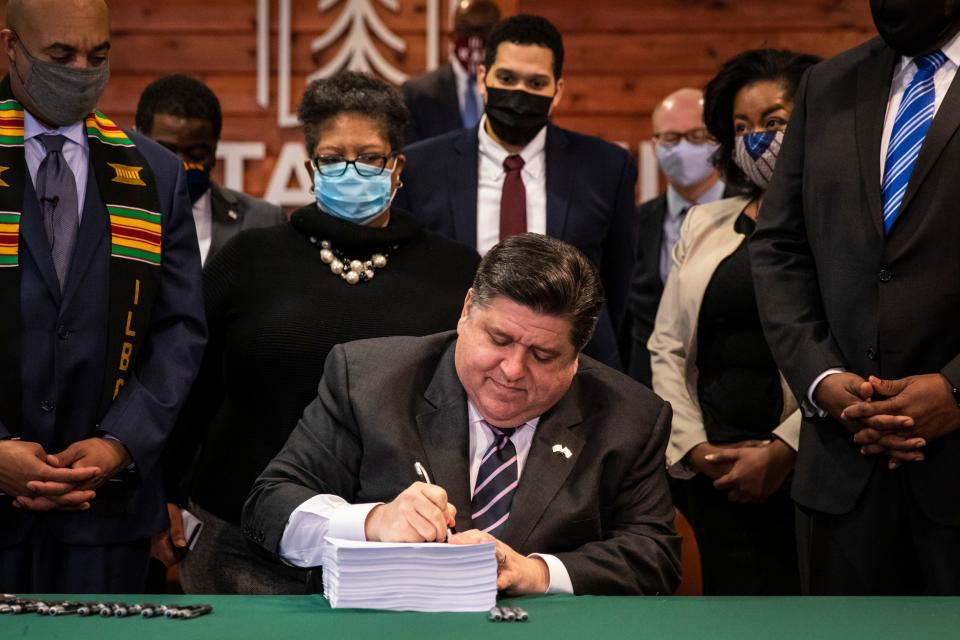 Flanked by lawmakers and supporters, Gov. J.B. Pritzker signs a sweeping criminal justice reform bill into law during a ceremony at Chicago State University on the South Side, Monday, Feb. 22, 2021. (Ashlee Rezin Garcia/Chicago Sun-Times via AP)