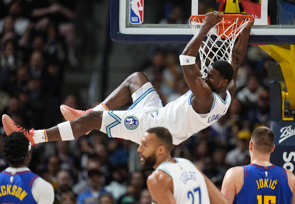 Minnesota Timberwolves guard Anthony Edwards hangs from the rim after dunking the ball for a basket in the first half of an NBA basketball game against the Denver Nuggets Friday, March 29, 2024, in Denver. (AP Photo/David Zalubowski)