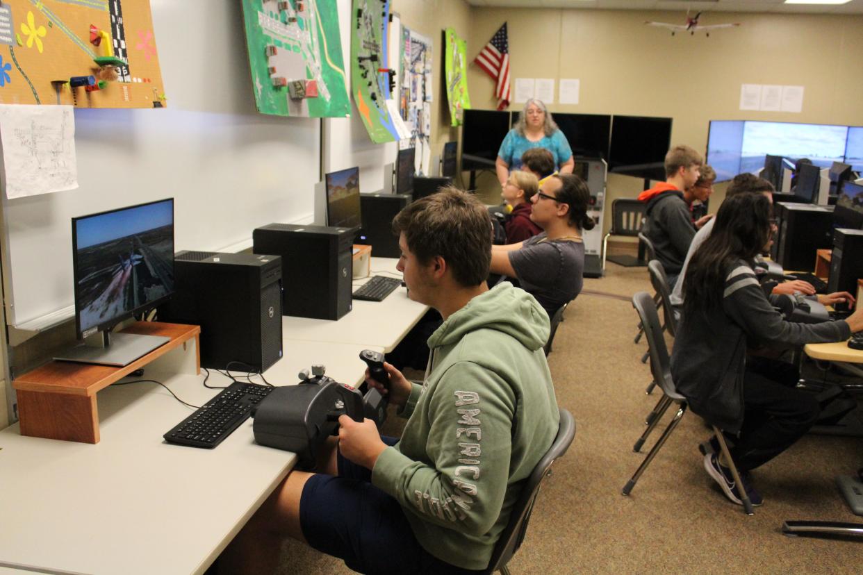 Laureen Mehlert (center, standing beneath the flag) commands the classroom as students simulate flight on computers in the classroom with the program X Plane 12, at the Career and Technical Education Academy on Wednesday, Sept. 27, 2023.