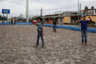 Children play in a basketball court covered with ash after Guatemala's Fuego volcano erupted violently, in Guatemala City, Guatemala June 3, 2018. REUTERS/Luis Echeverria