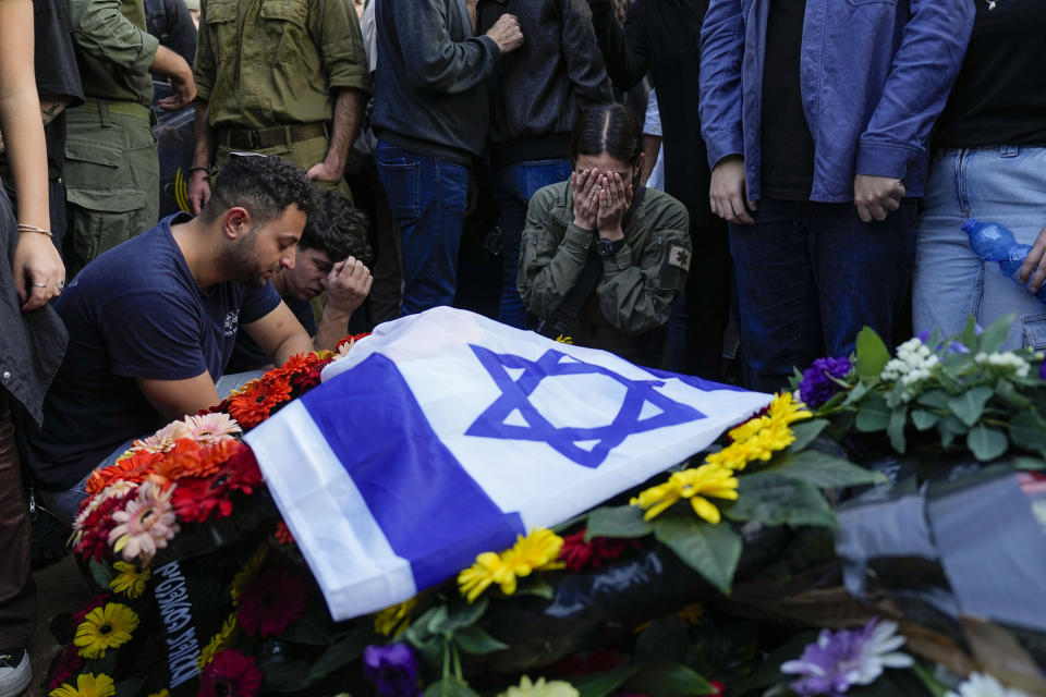 FILE - Mourners gather in grief around the grave of Israeli soldier Captain Harel Ittah during his funeral in Netanya, Israel, Sunday, Dec. 31, 2023. Israel's war on Hamas in the Gaza Strip has the Mideast simmering, raising the temperature on tensions across the region and increasing the risk that seemingly localized conflicts could spin out of control. (AP Photo/Ariel Schalit, File)