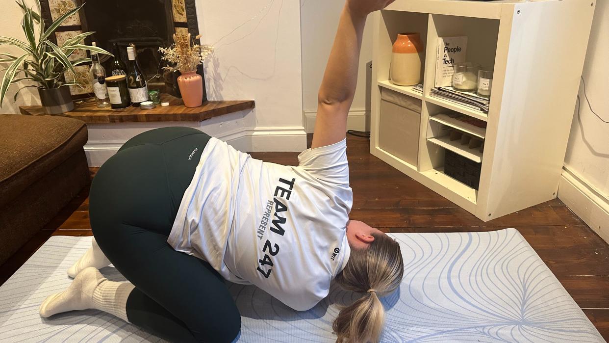  Alice Porter does thread the needle pose at home in living room. 