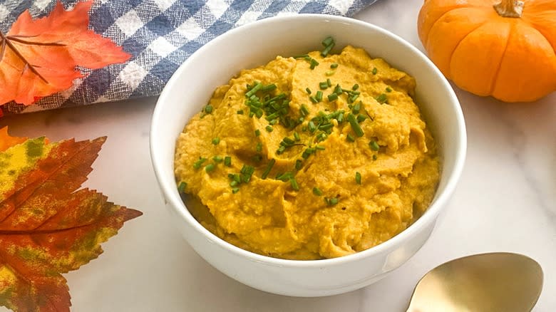 bowl of pumpkin hummus with fall leaves
