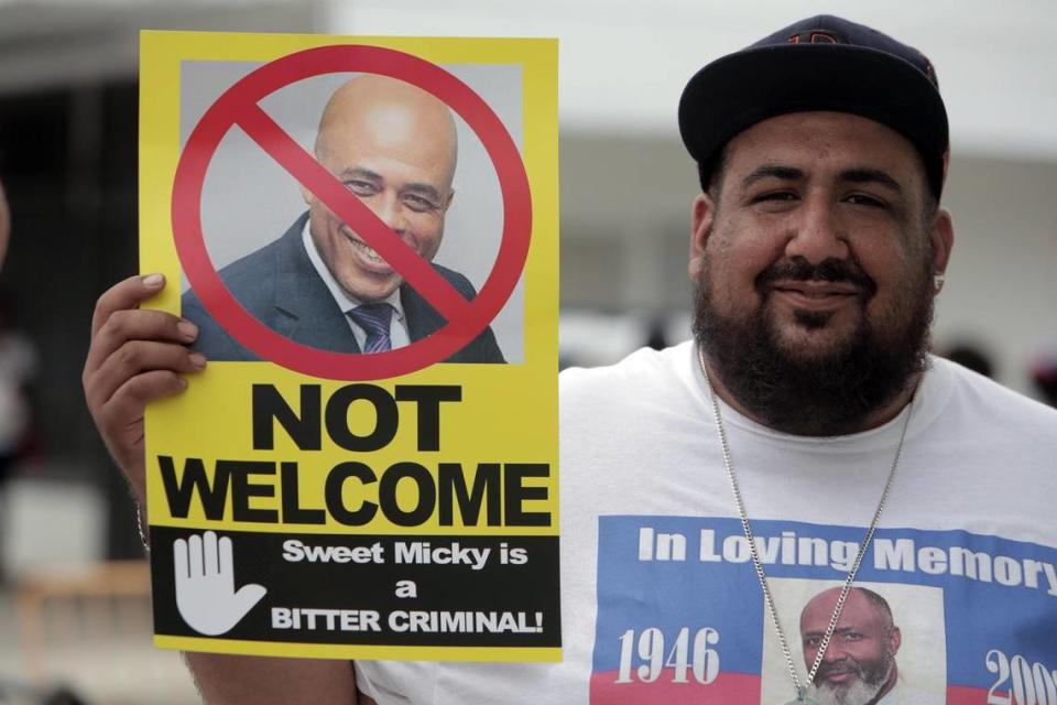 Michael Martinez of the Labor Community Alliance of South Florida protests the appearance of Michel Martelly during a Haitian Flag Day celebration at the Little Haiti Cultural Center Complex in 2018.