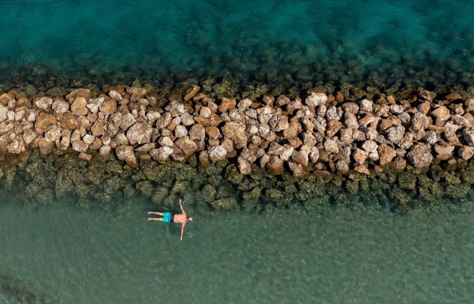 A snorkeler floats along the rocks watching the aquatic life in Dubois Park on October 26, 2021 in Jupiter, Florida.