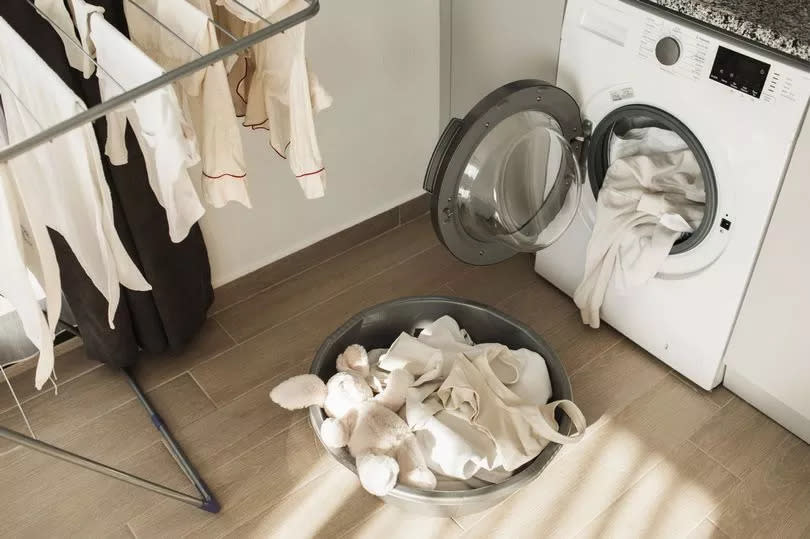 Laundry day on living room with washing machine, basket with clothes and drying clothesline