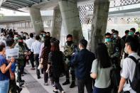 Office workers walk past riot police officers standing guard as a second reading of a controversial national anthem law takes place in Hong Kong