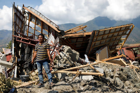 Kaharuddin, 40, waits for excavators to dig up a pile of concrete that used to be his home and was destroyed by an earthquake in Balaroa neighbourhood, Palu, Central Sulawesi, Indonesia, October 10, 2018. REUTERS/Jorge Silva