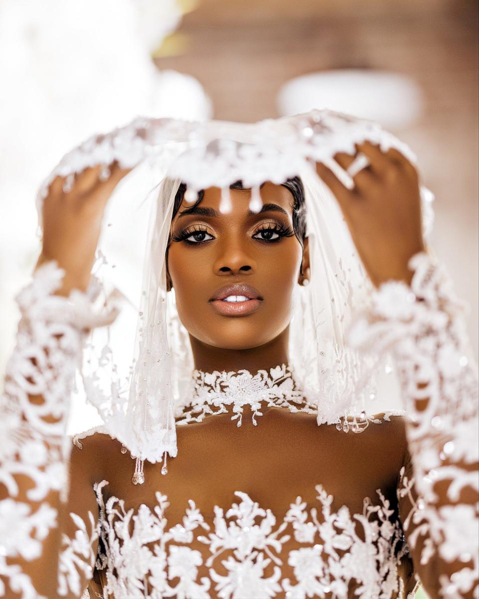 A bride lifts her veil so her face can be seen.