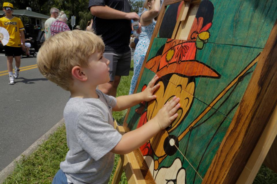 Declan Sullivan tries his hand at solving an interactive Mickey Mouse puzzle by artist Terry Fritts at the annual Mayfaire by-the-Lake festival on Saturday.