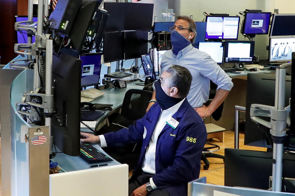 Traders wearing masks work, on the first day of in-person trading since the closure during the outbreak of the coronavirus disease (COVID-19) on the floor at the New York Stock Exchange (NYSE) in New York, U.S., May 26, 2020. REUTERS/Brendan McDermid