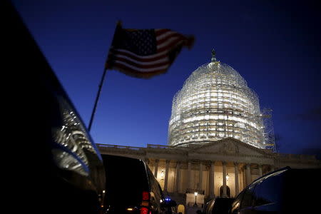 A U.S. flag on a vehicle flutters as the sun sets behind the U.S. Capitol dome in the hours before President Barack Obama delivers the State of the Union address to a joint session of Congress in Washington January 12, 2016. REUTERS/Jonathan Ernst