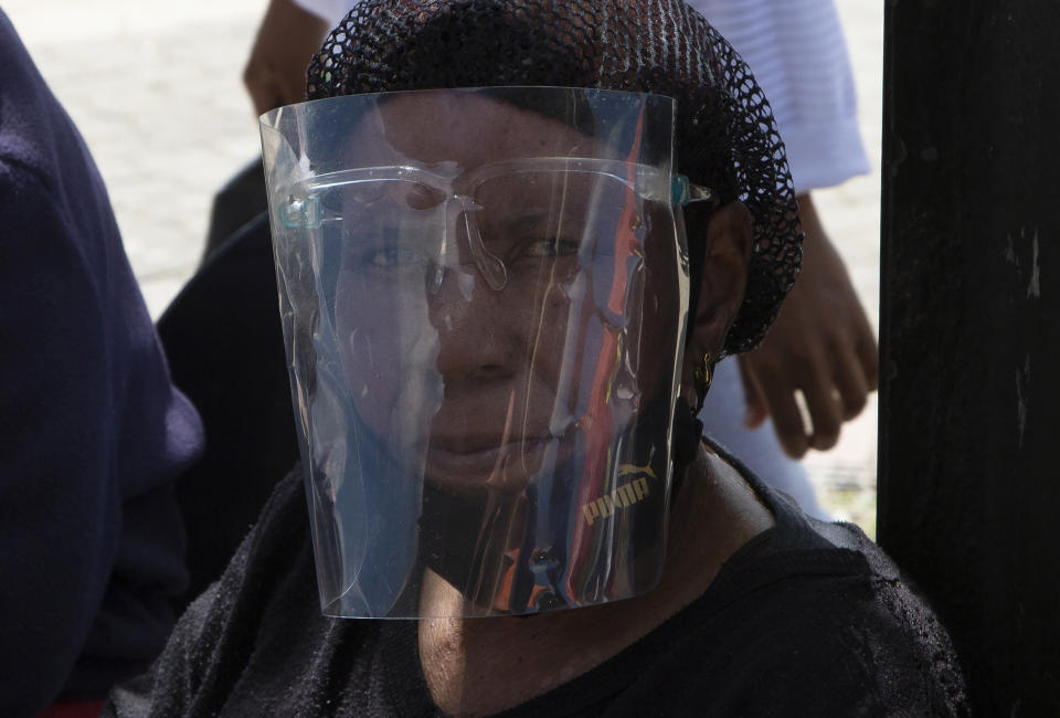 A woman wears a face shield to protect against COVID-19 at a taxi rank in Soweto, South Africa, Tuesday, April 5, 2022. 