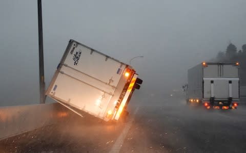 A truck turned over by high winds lies on a highway in Tomisato - Credit: AFP