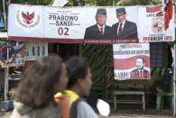 A couple rides a motorcycle past a campaign banners for Indonesian presidential candidate Prabowo Subianto, left, and his running mate Sandiaga Uno in Jakarta, Indonesia, Thursday, Jan. 17, 2019. Echoing the campaign tactics of Donald Trump, former Indonesian Gen. Subianto says his country, the world's third-largest democracy, is in dire shape and he is the leader who will restore it to greatness. (AP Photo/Achmad Ibrahim)