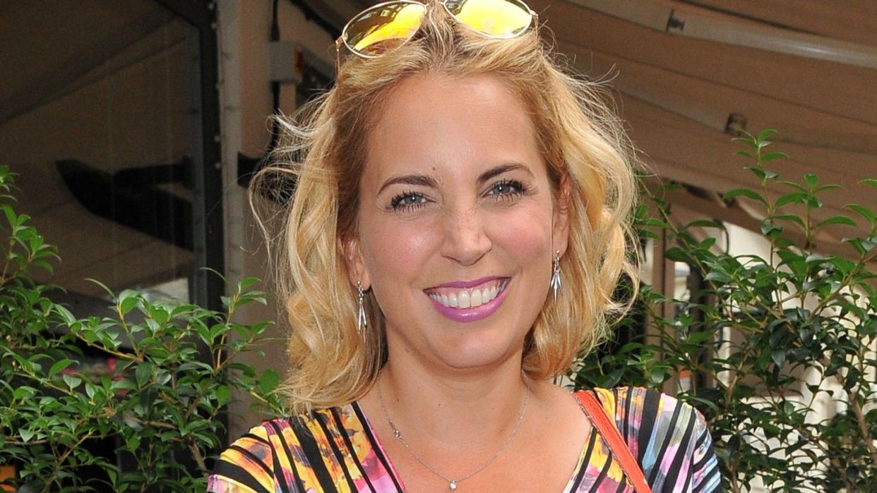 Jasmine Harman in a rainbow striped dress with sunglasses on her head