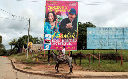 A boy rides his horse in front of a billboard for Nicaragua's President Daniel Ortega and his vice presidential candidate, first lady Rosario Murrillo in Ortega's childhood town of La Libertad, Nicaragua October 22, 2016. REUTERS/Oswaldo Rivas