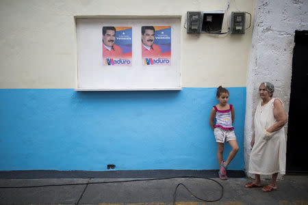 People stand next to campaign posters of Venezuela's President Nicolas Maduro during a campaign rally in Caracas, Venezuela May 16, 2018. Picture taken May 16, 2018. REUTERS/Carlos Garcia Rawlins