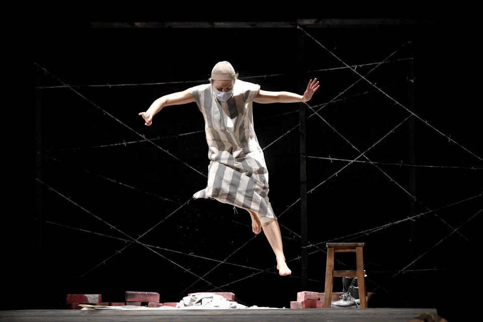 Alexandra Fasola of the Jewish State Theatre performs, wearing a face mask for protection against COVID-19 infection, during the premiere of the "The Beautiful Days of My Youth" play, based on the diary of Romanian Jewish Holocaust survivor Ana Novac, in Bucharest, Thursday, Oct. 15, 2020. The play premiered online and in front of spectators who took up less than a third of the seats because of measures meant to slow the second wave of the coronavirus pandemic in the eastern European nation. (AP Photo/Andreea Alexandru)