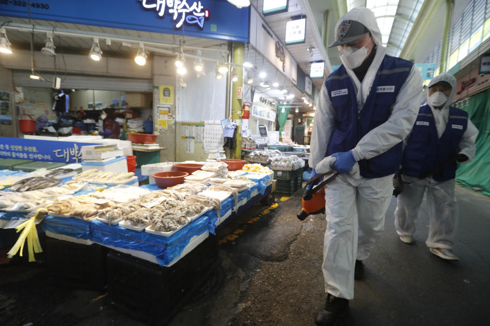 Workers wearing protective gears spray disinfectant as a precaution against the coronavirus at a market in Seoul, South Korea, Monday, Feb. 24, 2020. South Korean President Moon Jae-in said his government had increased its anti-virus alert level by one notch to “Red,” the highest level. It allows for the temporary closure of schools and reduced operation of public transportation and flights to and from South Korea. (AP Photo/Ahn Young-joon)