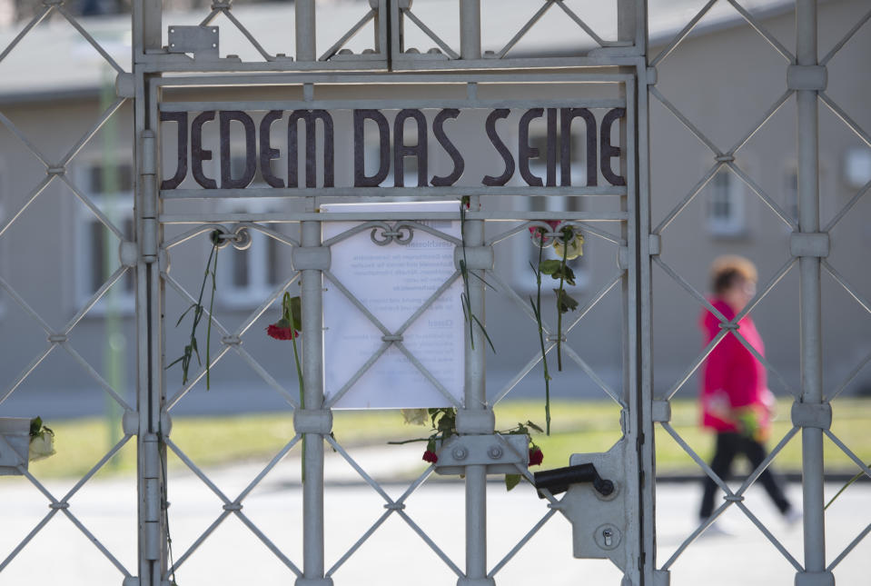 A woman walks behind the closed camp entrance with the slogan 'To Each His Own' (Jedem das Seine) at the 75th anniversary of the liberation of the former Nazi concentration camp Buchenwald by the US Army near Weimar, Germany, Saturday, April 11, 2020. Because of Corona crisis, the memorial is currently closed and all commemoration ceremonies with survivors have been cancelled. For most people, the new coronavirus causes only mild or moderate symptoms, such as fever and cough. For some, especially older adults and people with existing health problems, it can cause more severe illness, including pneumonia. (AP Photo/Jens Meyer)