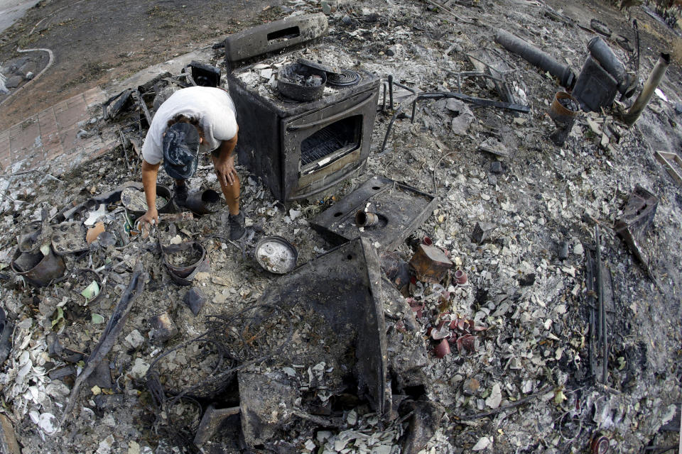 Bernadette Laos looks for salvageable items in her home that was destroyed by the Kincade Fire near Geyserville, Calif., Thursday, Oct. 31, 2019. The fire started last week near the town of Geyserville in Sonoma County north of San Francisco. (AP Photo/Charlie Riedel)