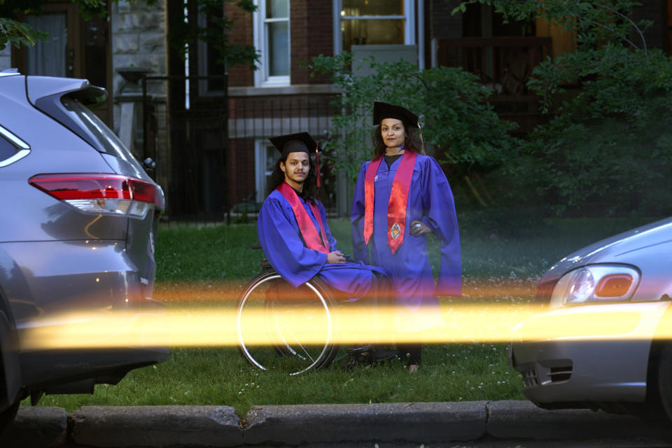 Jonathan Annicks and his mother Herlinda pose outside their home for a portrait wearing their cap and gowns just a few feet from where Jonathan was shot and paralyzed over six year-ago, Friday, June 10, 2022, in Chicago. Both graduated on Sunday, June 12 from DePaul University were Jonathan received his bachelor's degree in communications and media and Herlinda a Masters of Business Administration. (AP Photo/Charles Rex Arbogast)