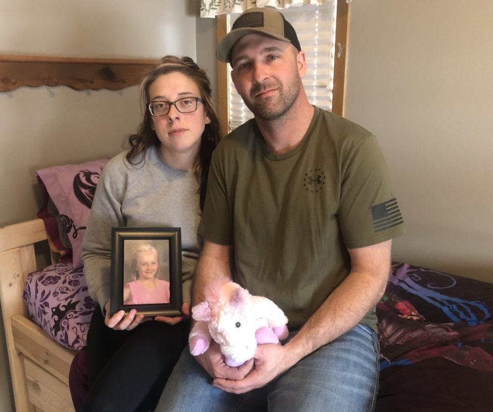 KaSandra and Chad Dennard hold a photo of Serenity and her favorite stuffed unicorn while sitting on her bed in their Sturgis home in this file photo.