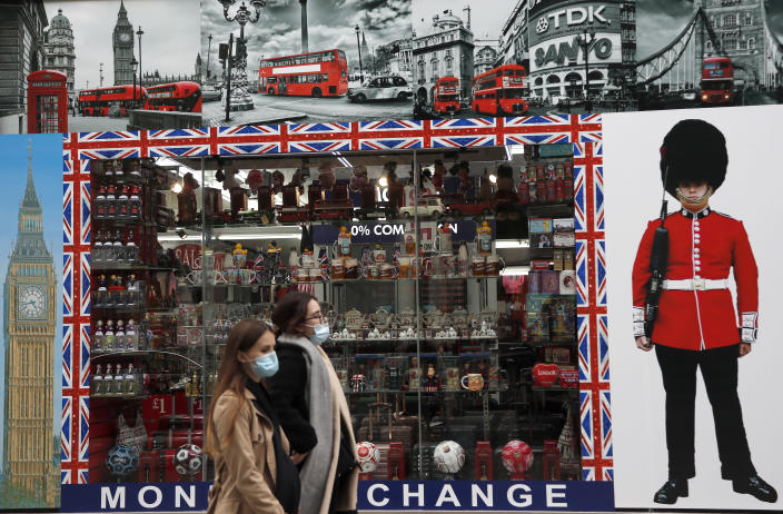 Shoppers walk past a shop window in Oxford Street, London, Tuesday, Oct. 13, 2020. Unemployment across the U.K. rose sharply in August which is a clear indication that the jobless rate is set to spike higher when a government salary-support scheme ends this month and new restrictions are imposed on local areas to suppress a resurgence of the coronavirus. (AP Photo/Frank Augstein)