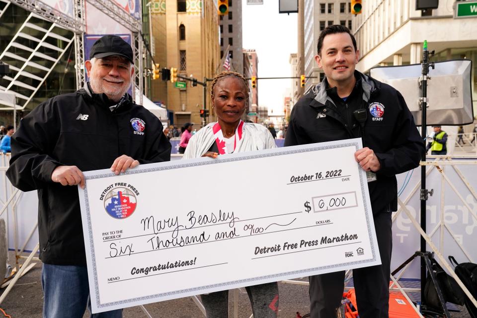 Detroit Free Press Editor and Vice President Peter Bhatia, left, presents a check to the women’s marathon winner Mary Beasley with Detroit Free Press executive race director Aaron Velthoven the 45th Annual Detroit Free Press Marathon in Detroit on Sunday, Oct. 16, 2022