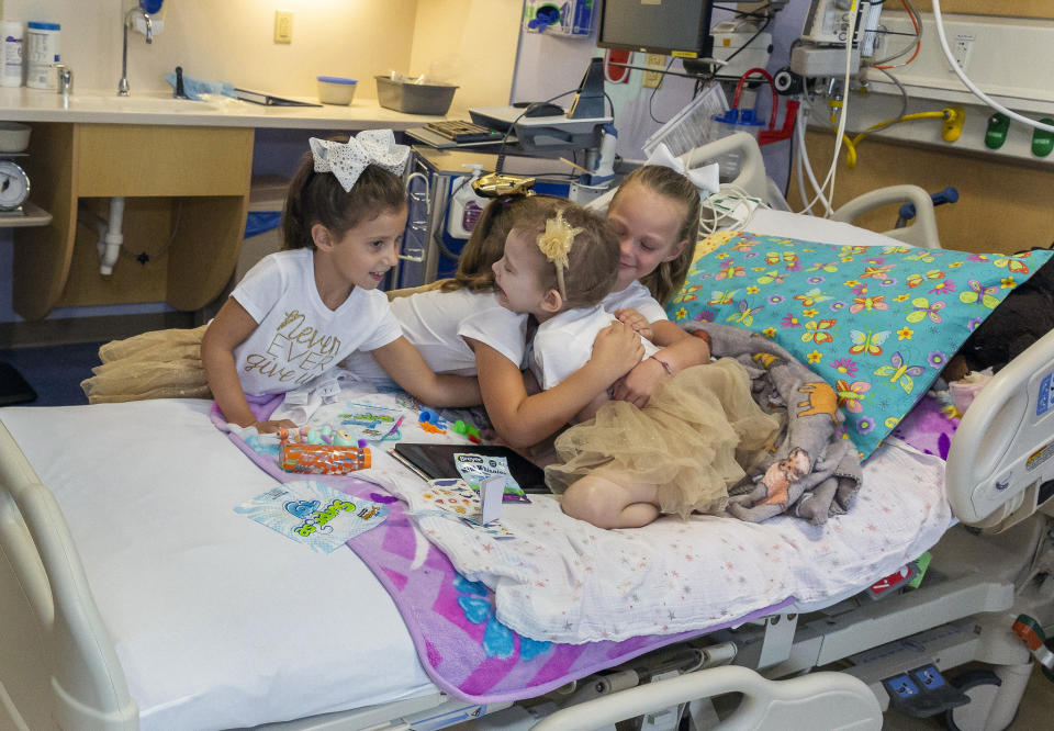 In this photo provided by Johns Hopkins All Children’s Hospital, Lauren Glynn is visited by friends Chloe Grimes, Avalynn Luciano and McKinley Moore in her room at the hospital in St. Petersburg, Fla., Aug. 28, 2019. The girls, who were diagnosed with cancer in 2016 and became fast friends while undergoing treatment, reunite every year. (Allyn DiVito/John Hopkins All Children's Hospital via AP)