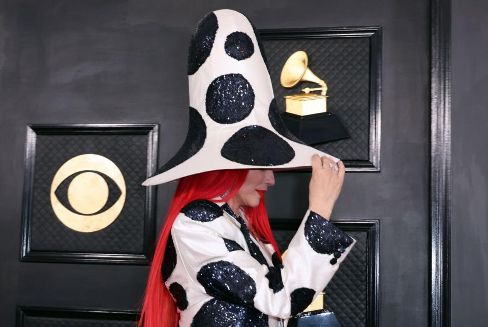 Shania Twain arrives to the show in a white top hat and dress with large black dots. Her wig is bright orange.