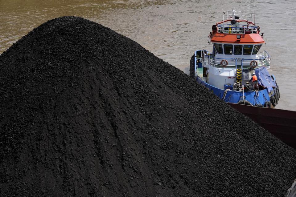 FILE - A tug boat pushes a barge carrying coal on Mahakam river in Samarinda, East Kalimantan, Indonesia, Dec. 19, 2022. A report released Wednesday, June 7, 2023, by the International Energy Agency says that demand for energy is growing, yet emissions are not growing as fast. (AP Photo/Dita Alangkara, File)