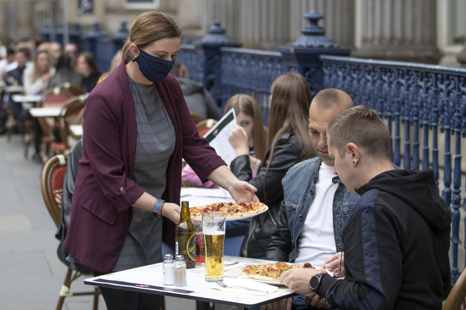 Meals are served at socially distanced tables on the street at Di Maggio's outdoor restaurant area in the city centre of Glasgow, Scotland, Monday July 6, 2020. Outdoor areas reopen to the public as Scotland continues with the gradual lifting of coronavirus lockdown restrictions with physical distancing measures. (Jane Barlow/PA via AP)