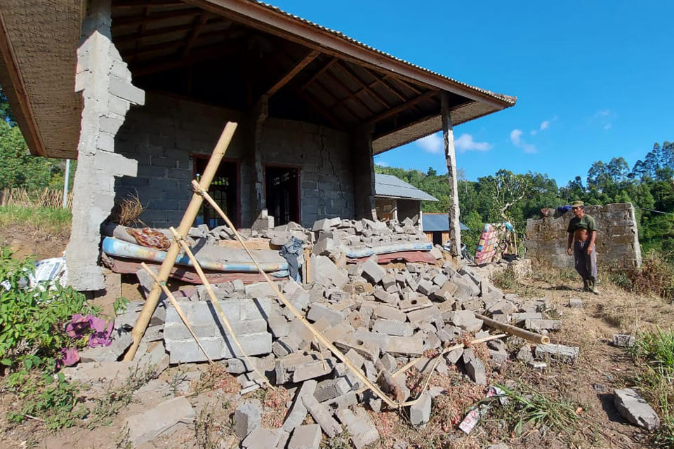 A man stands near his house damaged by an earthquake in Karangasem on the island of Bali, Indonesia, Saturday, Oct. 16, 2021. A few people were killed and another several were injured when a moderately strong earthquake and an aftershock hit the island early Saturday. (AP Photo/Andi Husein)