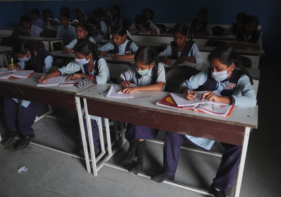 Indian students wear masks and attend a class at a government school in Hyderabad, India, Wednesday, March 4, 2020. A new virus first detected in China has infected more than 90,000 people globally and caused over 3,100 deaths. The World Health Organization has named the illness COVID-19, referring to its origin late last year and the coronavirus that causes it. (AP Photo/Mahesh Kumar A.)