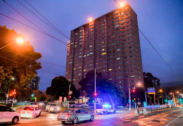 Police vehicles park outside one of nine public housing estates which have been locked down in Melbourne on July 4