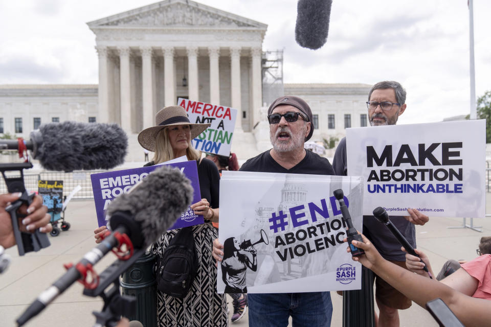 FILE - Rev. Patrick Mahoney, center, chief strategy officer for Stanton Healthcare, an Idaho-based pregnancy center that does not provide abortions, is flanked by Katie Mahoney, left, and supporter Kevin Krueger, right, as he speaks to the press outside the Supreme Court June 27, 2024, in Washington. A new poll finds that a solid majority of Americans oppose a federal abortion ban and that a rising number support access to abortions for any reason. (AP Photo/Mark Schiefelbein, File)