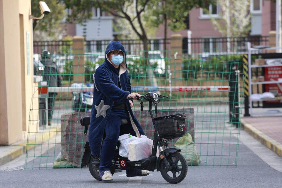 A man rides past a roadblock with his deliveries at a residential community under lock down in Shanghai, China, Tuesday, March 29, 2022. A two-phase lockdown of Shanghai's 26 million people is testing the limits of China's hard-line "zero-COVID" strategy, which is shaking markets far beyond the country's borders. (AP Photo)