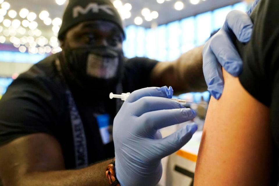 DeMarcus Hicks, a recent graduate of nursing school who is working as a contractor with the Federal Emergency Management Agency, gives a person a Pfizer COVID-19 vaccine booster shot, Dec. 20, 2021, at a vaccination clinic in Federal Way, Wash. (AP Photo/Ted S. Warren, File)