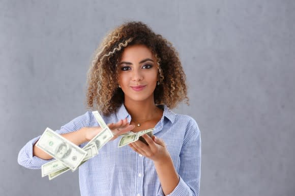 Woman tossing one hundred dollar bills out of her hand.