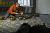 A man plays sounds as soldiers lie in a room at a clinic which treats veterans for PTSD, post-combat stress and post-concussion trauma, in Kyiv, Ukraine, Monday, Nov. 21, 2022. When peace returns to Ukraine, many thousands of its combatants will likely return with psychological scars from the battlefields. A mental health rehabilitation center for soldiers on the outskirts of Ukraine's capital, Kyiv, treats post-traumatic disorders with acupuncture, soothing sounds and other therapies. (AP Photo/John Leicester)