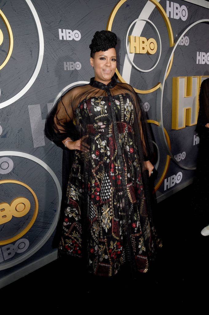 Natasha wearing a patterned dress with a see-through overlay as she poses for photographers on the red carpet