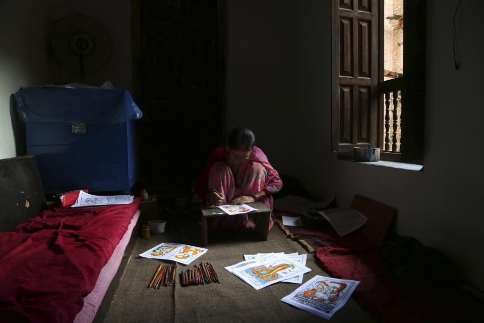 In this July 31, 2019, photo, Tej Kumari Chitrakar makes traditional paintings ahead of Naag Panchami festival at her residence in Bhaktapur, Nepal. Chitrakar families in the Nepalese capital of Kathmandu were renowned traditional painters and sculptors who depicted gods and goddesses on temples, masks of Hindu deities and posters for various religious celebrations. For Tej Kumari and her husband it is a struggle to keep the dying art alive against the modern mass produced prints. (AP Photo/Niranjan Shrestha)