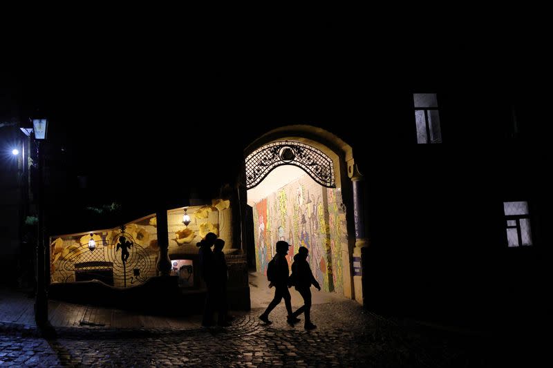 People walk on a dark street in the old town of Kyiv