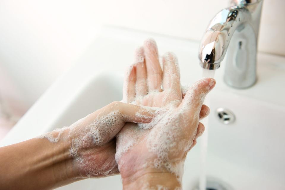 Washing of hands with soap under running water.