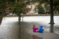 Azalea Sowers, 7, and Isak Asmundsson, 7, sit in the middle of Mowbray Arch in Norfolk, Va., which flooded as a result of the storms caused by Hurricane Dorian on Friday, Sept. 6, 2019. (Sarah Holm/The Virginian-Pilot via AP)