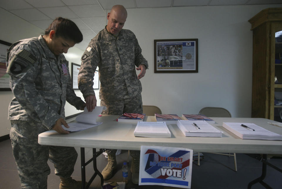 A U.S. service member (left) checks a ballot before filling it out at a U.S. military base in Afghanistan on Oct. 15, 2008. U.S. soldiers, aid workers and military contractors overseas have been allowed extra time for their ballots to arrive at election offices in the U.S. (Photo: Rafiq Maqbool/ASSOCIATED PRESS)