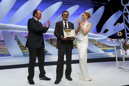 Director Nuri Bilge Ceylan (C), Palme d'Or award winner for his film "Winter Sleep", poses on stage surrounded by director Quentin Tarantino (L) and actress Uma Thurman (R) during the closing ceremony of the 67th Cannes Film Festival in Cannes May 24, 2014. REUTERS/Yves Herman